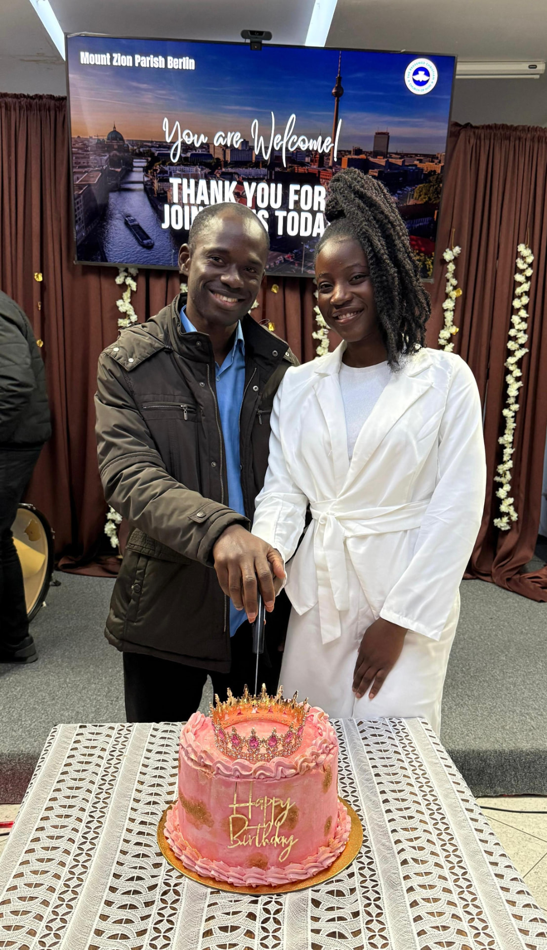 Busolami and Tunde cutting a pink birthday cake together in Berlin